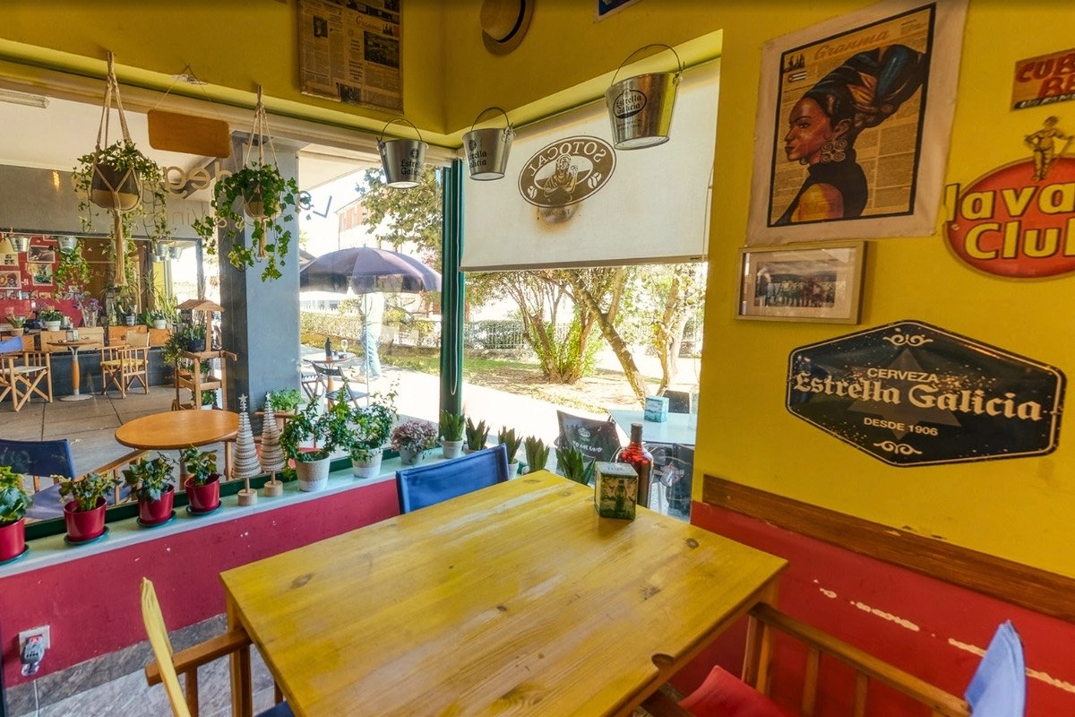 Mesa à janela com vista para o jardim e parede amarela com memorabilia cubana