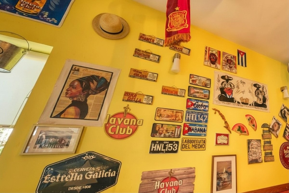 Parede amarela com matrículas cubanas, Havana Club e um chapéu de palha